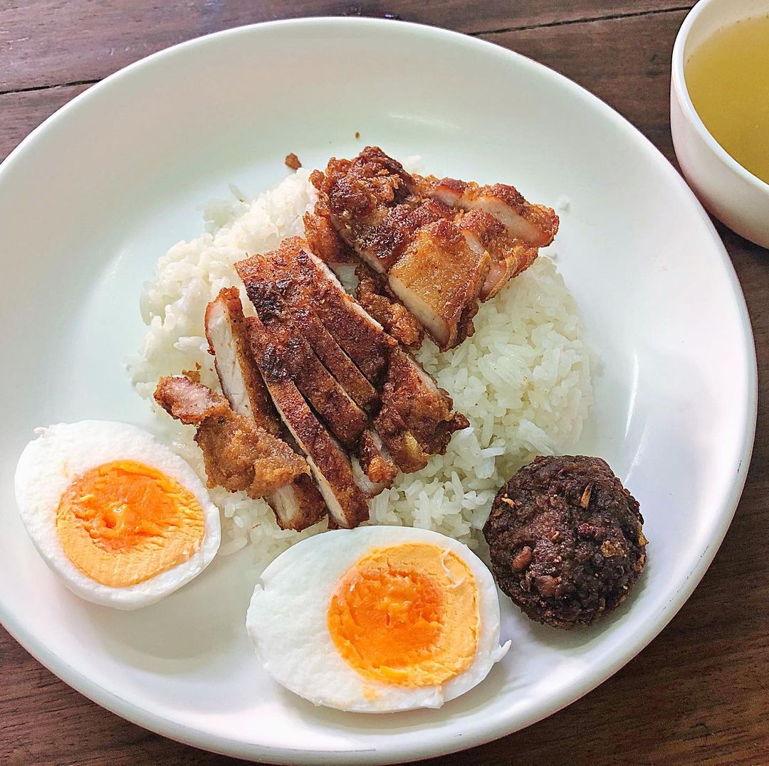 A plate of fried pork and a hard-boiled egg atop a bed of rice from Baan Khaek Fried Pork. 