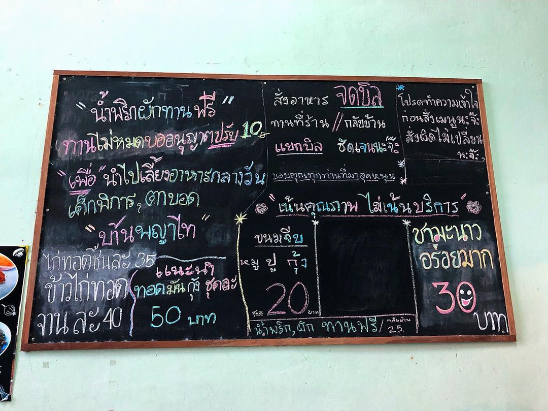 A blackboard showing Baan Khaek Fried Pork's affordable menu of food items. 