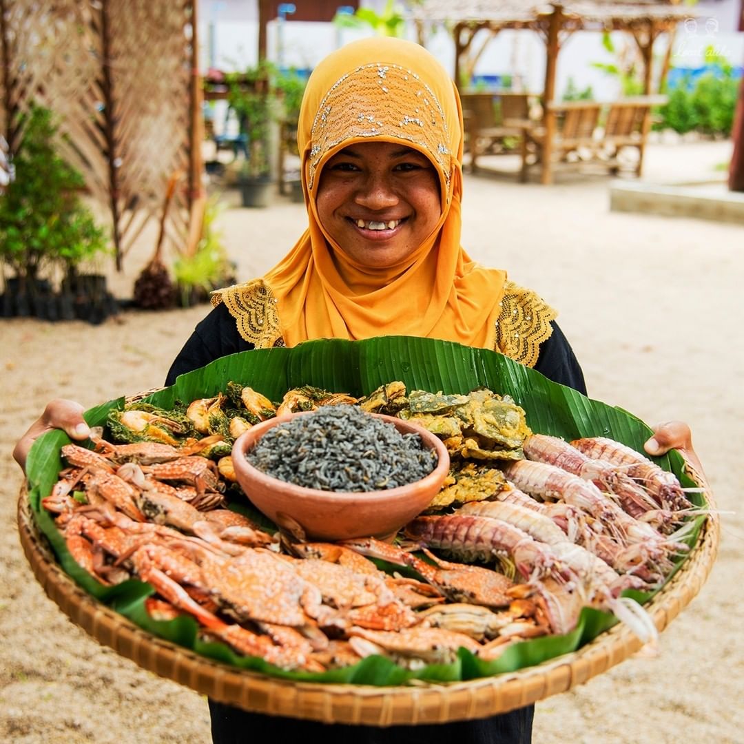 A local village from the Baan Laem community showing off their specialty: Mud-coloured rice with a seafood platter.
