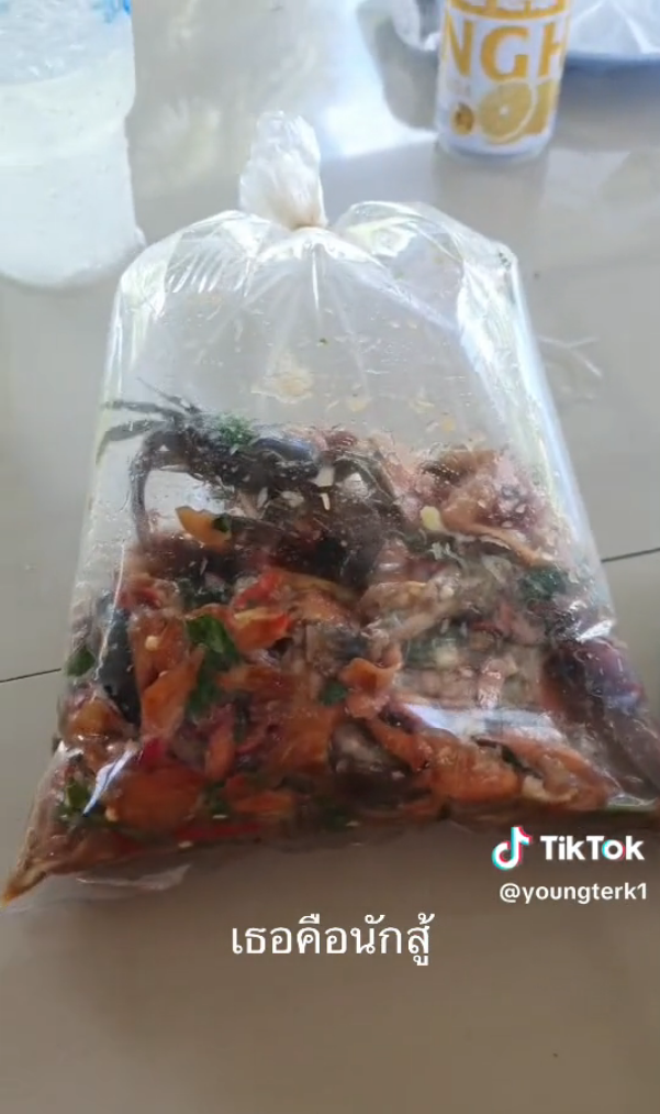 A crab scurrying away from the camera in a bag of somtam.