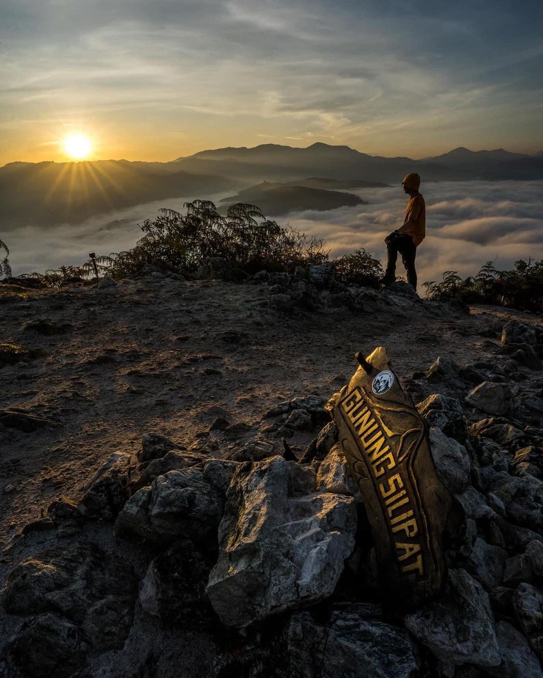 A man making camp on top of Gunung Silipat as the sun sets in Southern Thailand. 