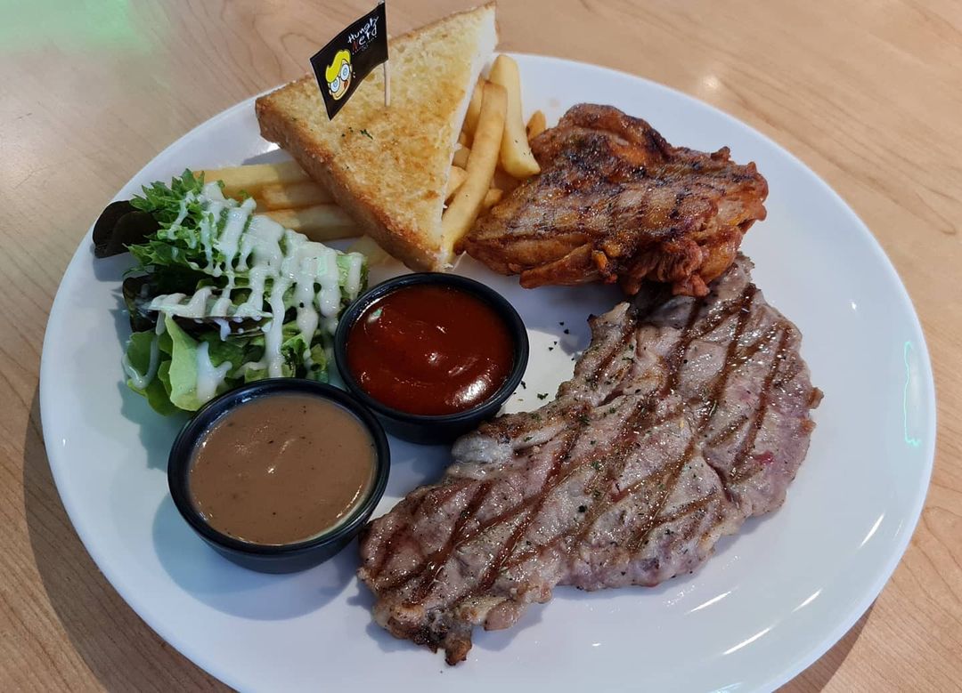 A plate of pork and chicken steak with a salad, bread, and fries at the Hungry Nerd. 
