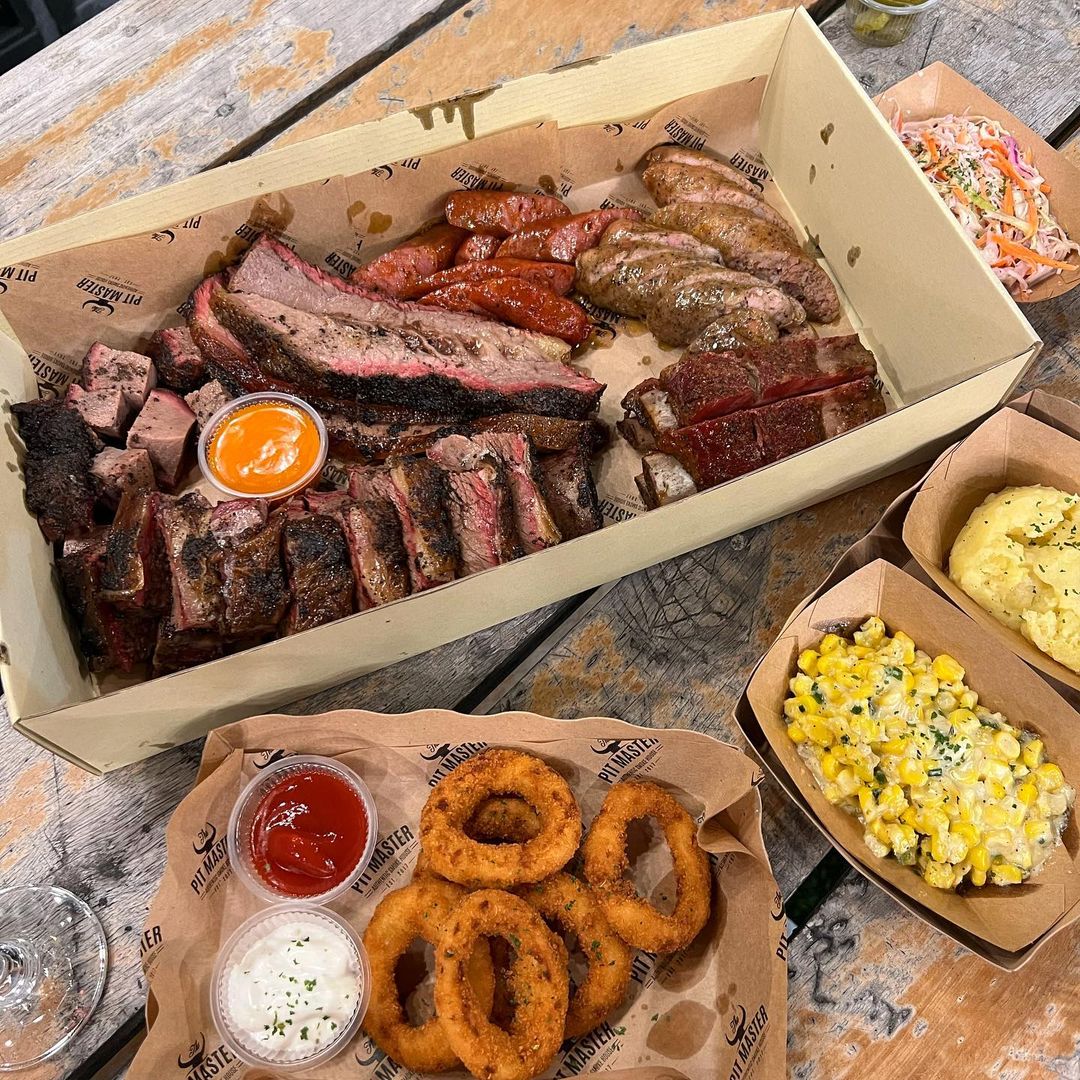 A platter of smoked meats from PIT Master with a huge variety of sides including cream corn and mashed potatoes at PIT Master.