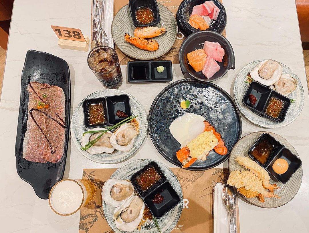 A platter of international dishes including lobster, sashimi, and wagyu beef. 