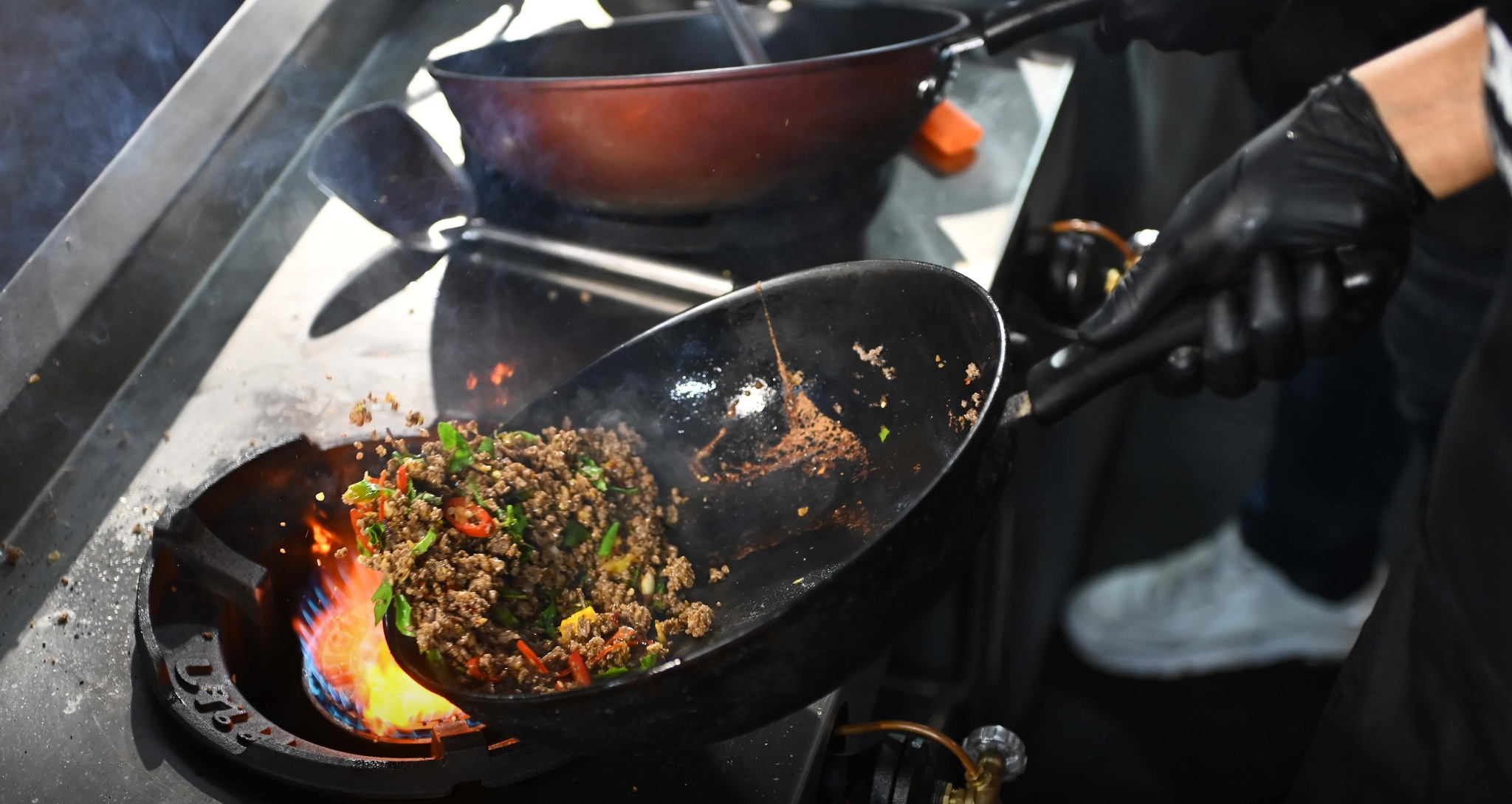 A chef working a wok to cook up pad krapao. 