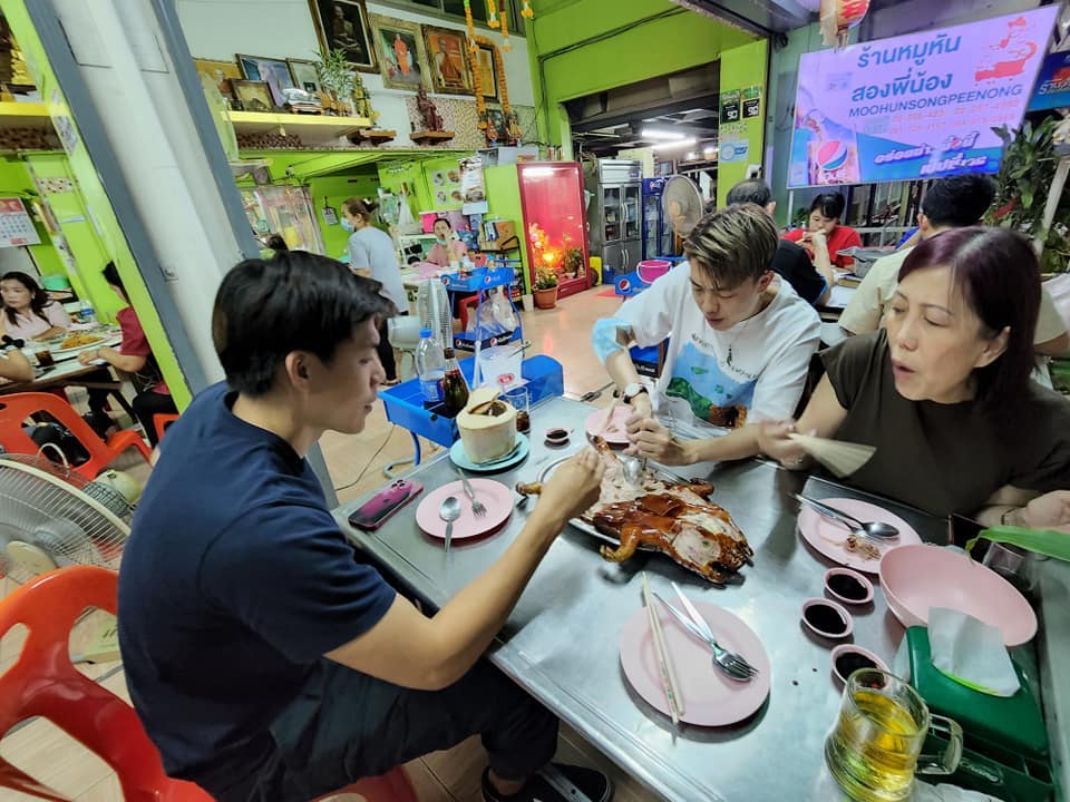 A group of friends sharing Moo Hun Song Pee Nong's signature pork dish. 